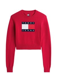 Roter gestrickter Pullover mit einem gerippten Saum und Bündchen. In der Mitte befindet sich ein rechteckiges Logo-Patch in Marineblau, Weiß und Rot.