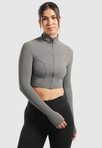 Graue, kurz geschnittene Sportjacke mit langen Ärmeln und hohem Kragen; sie verfügt über einen Frontreißverschluss und strukturierte Paneele.