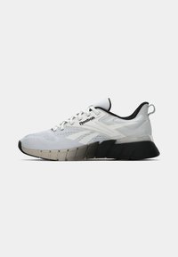 Pantofii sport albi cu un bovenă din plasă respirabilă, accente negre și o talpă groasă, texturată, pentru amortizare și suport. Prezintă brandingul Reebok.