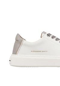 Sneaker in pelle bianca con un morbido accento grigio, caratterizzata da una suola bianca spessa, lacci grigi e il marchio in oro embossato "ALEXANDER SMITH."