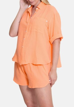 Perzikkleurig shirt met korte mouwen, knopen en een zak, gecombineerd met bijpassende shorts. Zacht, gestructureerd materiaal. Casual, ontspannen pasvorm.