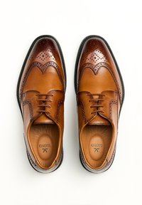 Bruine leren dresschoenen met brogue-afwerking, een gladde afwerking, vetersluiting, ronde neus en een contrasterende zwarte zool.