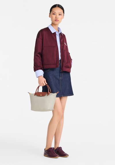 Burgundy satin bomber jacket, light blue shirt, denim skirt, gray handbag with brown leather accents, and maroon sneakers.