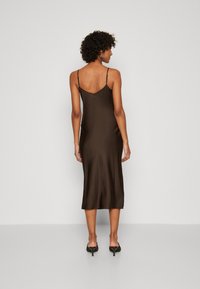 Robe midi en satin marron avec des bretelles spaghetti fines, une coupe droite et une texture lisse. Présente un dos plongeant et arrive juste en dessous du genou.