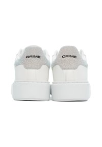Zapatillas de cuero blanco con un tab de talón texturizado en plata y el logo negro "CRIME". Presentan una suela blanca gruesa y un diseño minimalista.