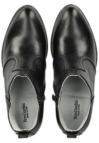 Botas de tobillo de cuero negro con un acabado suave, puntera afilada, costuras decorativas y cierre de cremallera en el lateral. El interior presenta un forro gris.