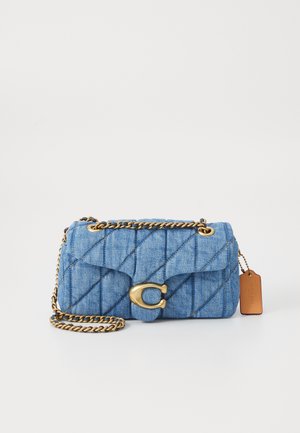 Bolso de mano de mezclilla azul acolchado con asa de cadena dorada, cierre dorado en forma de C y etiqueta de marca de cuero marrón sobre fondo blanco.