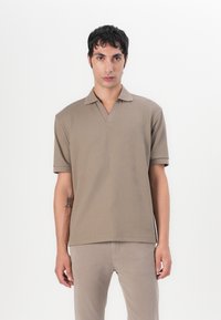 Polo tričko s krátkými rukávy v strukturované béžové látce s designem do V. Přiléhavý střih s žebrovanými manžetami, žádné viditelné logo ani vzory.