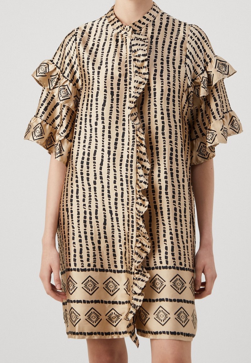 Robe en satin avec une base dorée claire, présentant des rayures verticales noires, des manches à volants et un ourlet à motif géométrique.