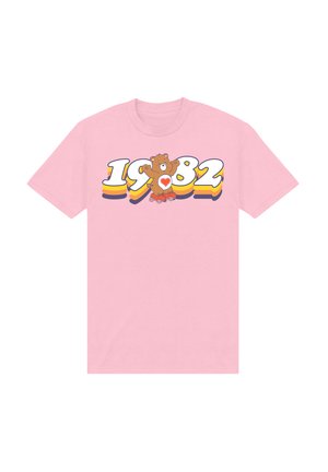 Lyserød bomulds t-shirt med et grafisk motiv af en teddybjørn og teksten "1982" i livlige farver og et legende design. Korte ærmer og rund hals.