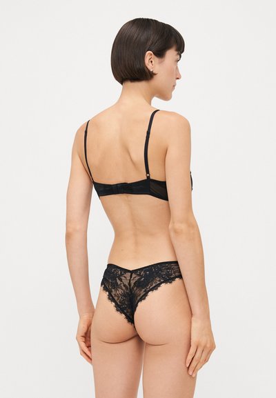 Black lace lingerie set featuring a bra with adjustable straps and hook closure, paired with matching lace thong, sheer with floral pattern.