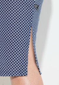 Falda de patrón navy hecha de tela suave, con un estampado geométrico en blanco, con una abertura lateral y etiqueta visible en la cinturilla.