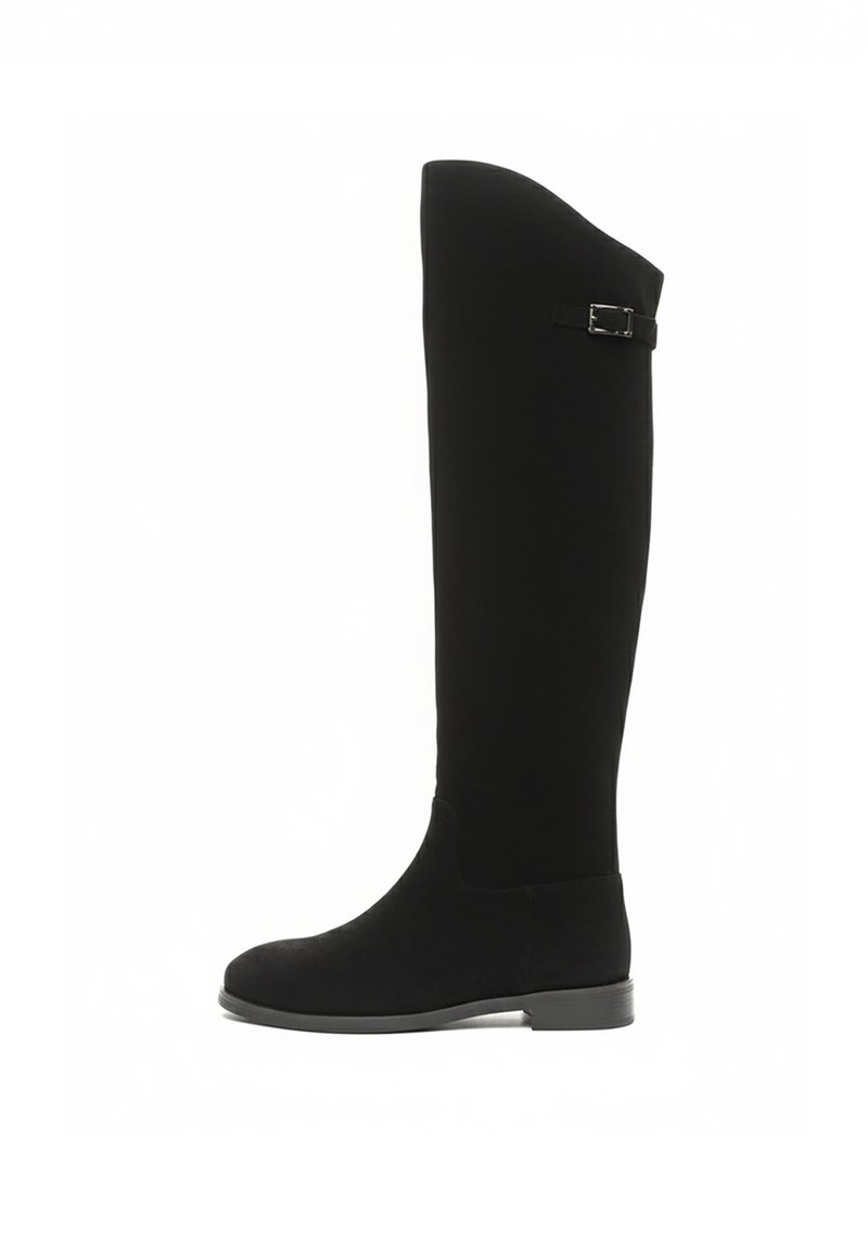 Bottes noires montantes au-dessus du genou en daim doux ; semelle plate, bout arrondi et un accent avec une boucle sur le côté extérieur. Texture lisse.