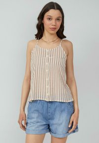 Gestreept tanktop in beige en lichtbruin, met een knoopsluiting aan de voorkant, dunne bandjes en een losse pasvorm. Gecombineerd met denim shorts.