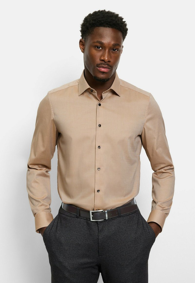 Beige long-sleeve dress shirt with a subtle pattern, button-up front, and black buttons, worn with dark gray trousers and a brown belt.