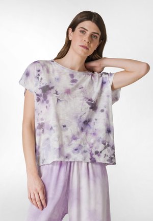 Lehký top s krátkým rukávem v bílém a levandulovém tie-dye vzoru, s volným střihem a měkkou texturou, doplněný o odpovídající levandulové spodní díly.