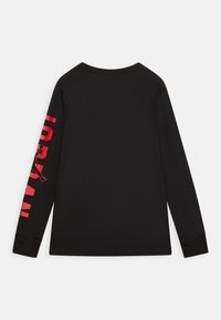 Černá dlouhá rukávová košile z bavlny, s pevným zadním dílem a výrazným červeným textem na levém rukávu. Jednoduchý design s kulatým výstřihem.