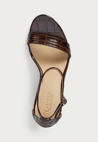 Sandal in pelle stampata coccodrillo marrone con una larga fascia, punta aperta e fibbia regolabile alla caviglia. Soletta beige liscia con impronta del logo.