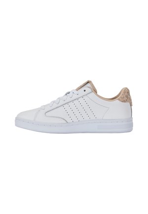 Zapatilla blanca de corte bajo con detalles en beige, rayas perforadas en el lateral y cierre de cordones, mostrada desde el lado exterior.