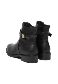 Čierne kožené členkové čižmy s hladkým povrchom, so bočným zipsom a pozlátenou sponou na obvinatej páske. Nízky blokový podpätok.