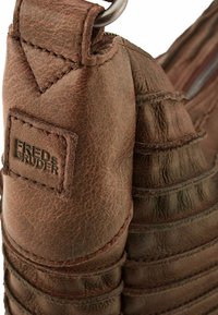 Borsa in pelle marrone con una superficie testurizzata, dettagli cuciti e una patch con logo. Include un anello in metallo e una chiusura con zip.
