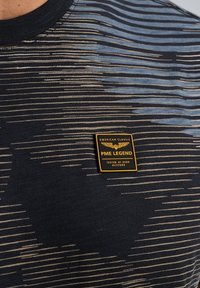 Black T-shirt features horizontal stripes in blue and beige. Includes a yellow and black PME Legend label on the left side.