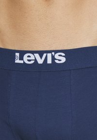 Marineblaue Baumwoll-Boxershorts mit einem weißen Levi's-Logo-Bund, ausgestattet mit flachen Nähten und einer glatten Textur.