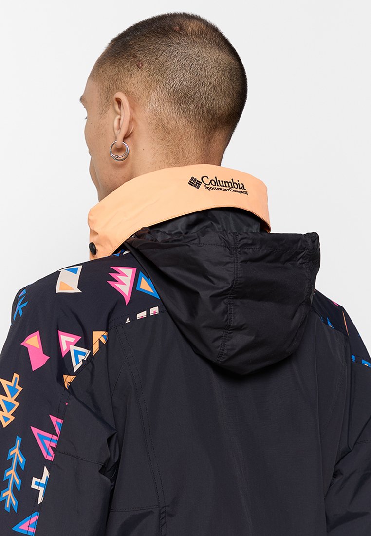 Czarna kurtka z pomarańczowym kołnierzem, z kolorowymi geometrycznymi wzorami na rękawach. Logo umieszczone na kołnierzu. Posiada kaptur.