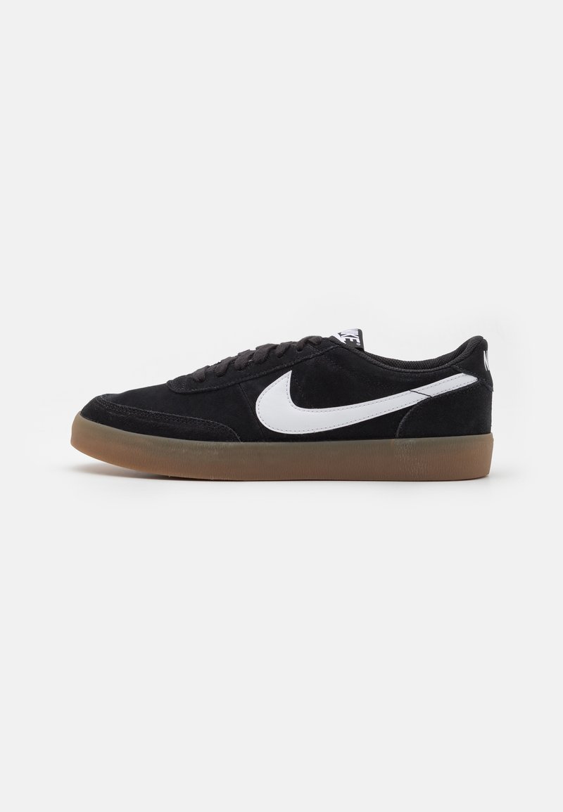 Baskets basses noires avec logo Nike blanc, semelle en gomme et lacets noirs, présentées de profil sur fond uni.