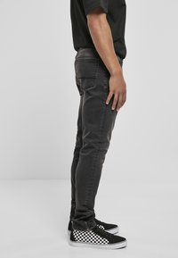 Mustat farkut, joissa on slim fit -leikkaus, hienovaraista kulutusta, takataskut, ja yhdistetty mustavalkoisiin ruutukenkiin.
