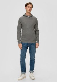 Light gray knit hoodie with a relaxed fit, layered over a white shirt. Paired with blue jeans and white sneakers. Soft texture and casual design.