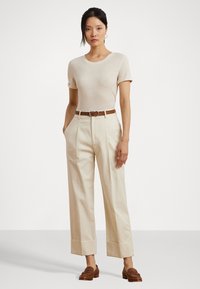 Beige short-sleeve T-shirt paired with high-waisted, cream trousers featuring a wide leg and cuffed hem, secured with a brown belt.
