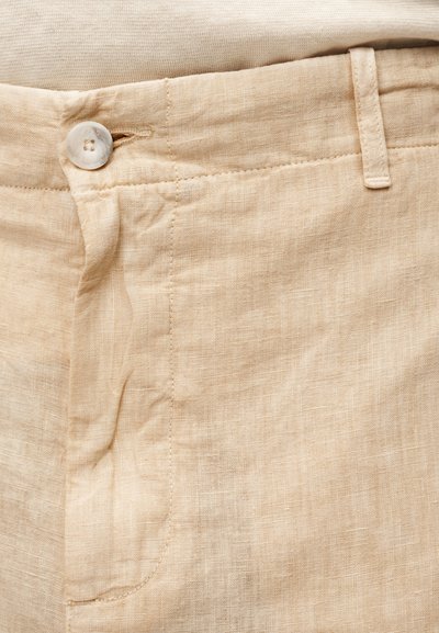 Μπεζ λινά παντελόνια με κλείσιμο με κουμπί, που διαθέτουν διακριτική υφή και ραφές κατά μήκος της μέσης και των τσεπών.
