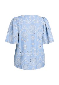Blusa azzurra chiara con maniche corte a sbuffo, caratterizzata da ricami floreali bianchi e dettagli a ritaglio in un motivo circolare su tutta la superficie.