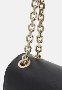 Musta nahkainen käsilaukku, jossa on koristeellinen tekstuuri, ja kullanvärinen ketjusanka, jonka linkit ovat lomittain sekä metallikoristeet.