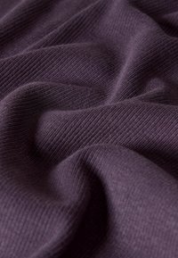 Tela de color púrpura con un relieve suave, que muestra pliegues y arrugas suaves, enfatizando su elasticidad y flexibilidad.