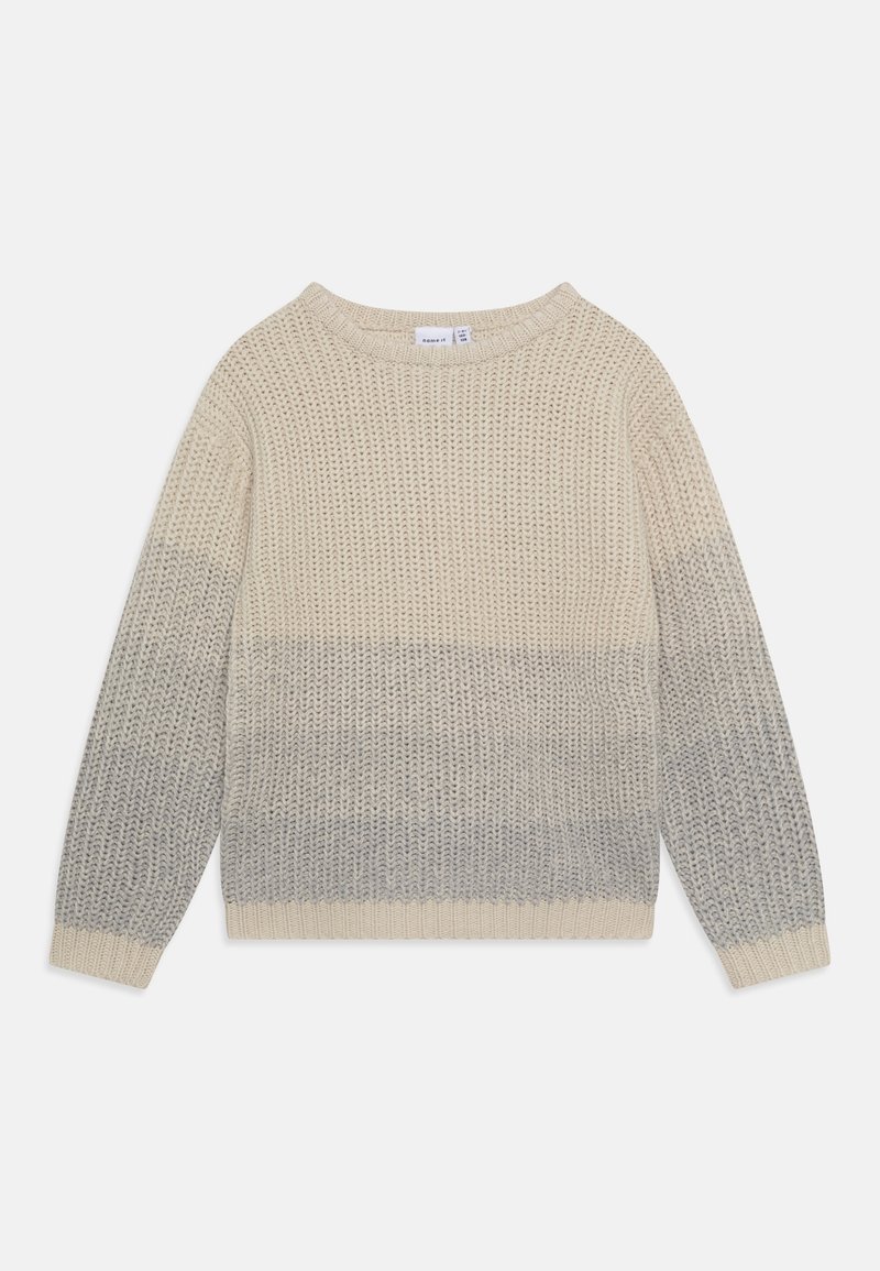 Pull en grosse maille à manches longues, col rond, avec un dégradé de couleurs allant du crème en haut au gris clair en bas sur fond blanc.