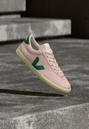Lichtroze leren sneaker met groene accenten en witte veters. Voorzien van een getextureerde neuskap en een geribbelde beige rubberen zool.