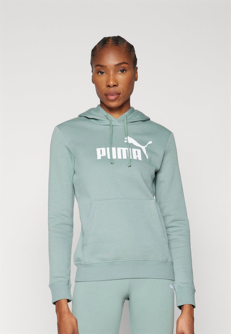 Zelená mikina s kapucňou, predným vreckom a bielym logom Puma. Mäkká tkanina, priliehavé manžety a spodný lem. Súčasť športovej sady.