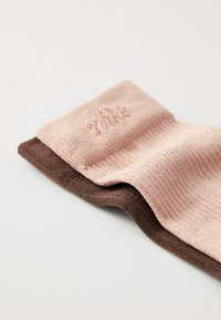 Pairs of socks featuring a light pink top section and a dark brown section, with a textured knit pattern and subtle embossed detail.