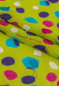 Tessuto verde vivace con grandi pois in rosa, viola, blu e bianco. Presenta un logo visibile "Manila Grace." Texture morbida.