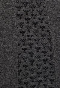 Tessuto grigio con un motivo nero testurizzato e piccoli elementi floreali, creando un sottile contrasto e una superficie tattile.