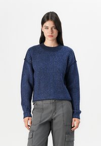 Maglione a coste blu navy con collo rotondo e spalle basse; le maniche lunghe presentano polsini arrotolati; texture morbida e vestibilità comoda.