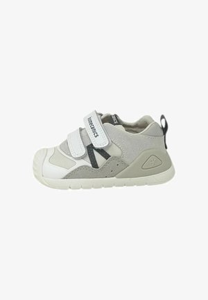 Sneaker grigia e bianca per bambini con due cinturini in Velcro, dettagli neri, suola imbottita e un anello sul tallone per facilitarne la calzata.