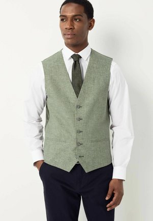 Green textured vest with six buttons, worn over a white dress shirt and paired with a dark patterned tie. Flat front design, no visible pockets.