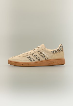 Bézs Adidas Spezial sportcipő zsiráfmintás csíkokkal és sarokkal, gumitalppal, valamint fehér "Spezial" szöveggel az oldalon.