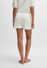 Vita, lätta shorts med elastisk midjeband, med en avslappnad passform och mjuk textur, sedd bakifrån.