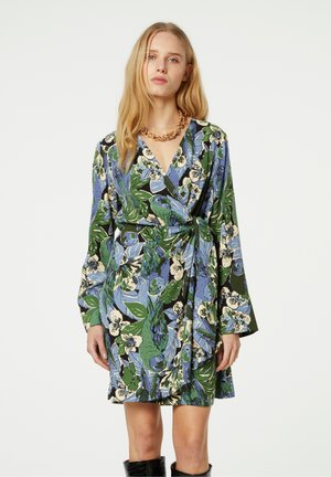 Floral wrap dress featuring a green, blue, and cream color palette. Long sleeves, v-neck, and knotted waist with a soft fabric texture.