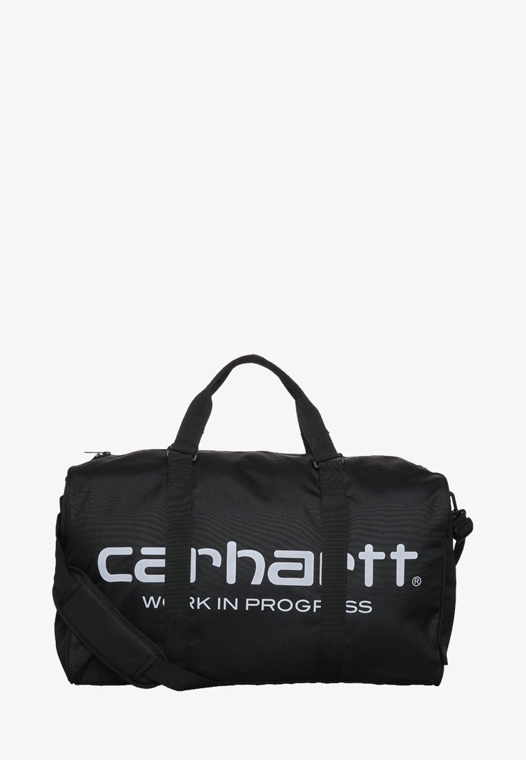 Bolsa de deporte negra hecha de tela resistente, con dos asas superiores y una correa para el hombro ajustable. Logotipo blanco prominente de "Carhartt" impreso en el lateral.
