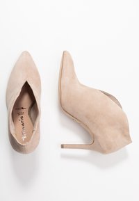 Beige suede high-heeled shoes with a pointed toe design, featuring a smooth texture and a thin stiletto heel.